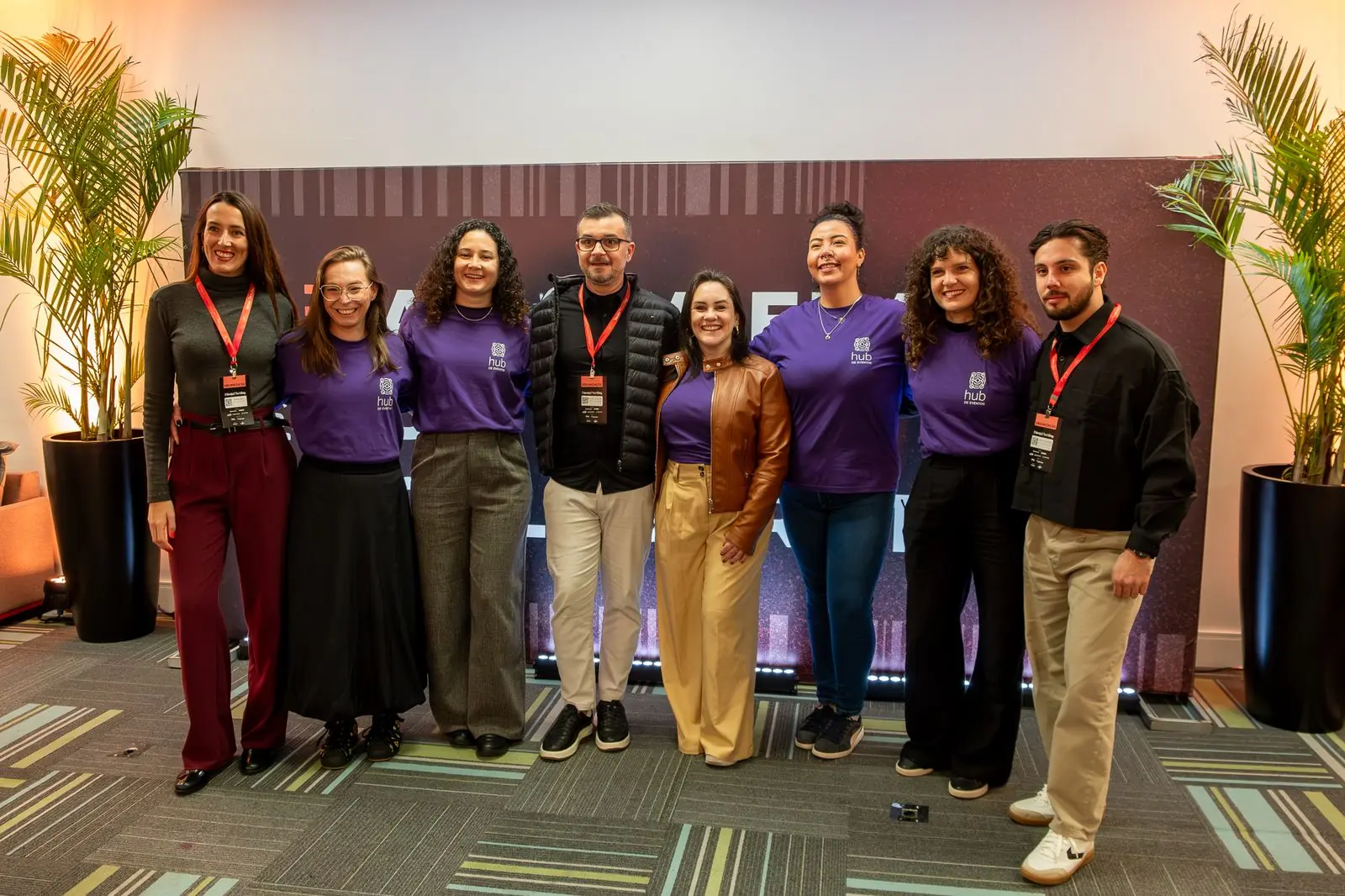 Equipe de produção reunida em frente ao painel do evento