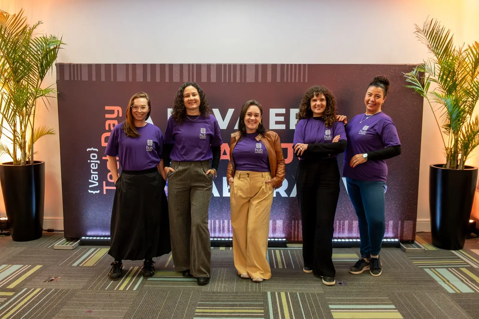 Equipe em frente ao painel de marca do Varejo TechDay